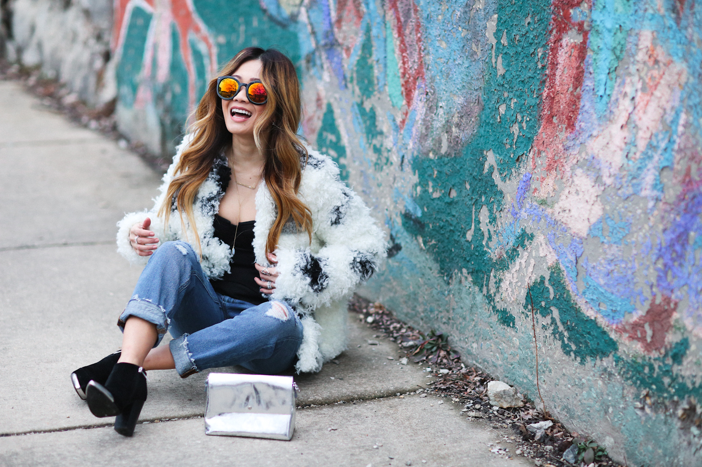 corset top and curly faux fur coat with reflective sunglasses and ripped jeans