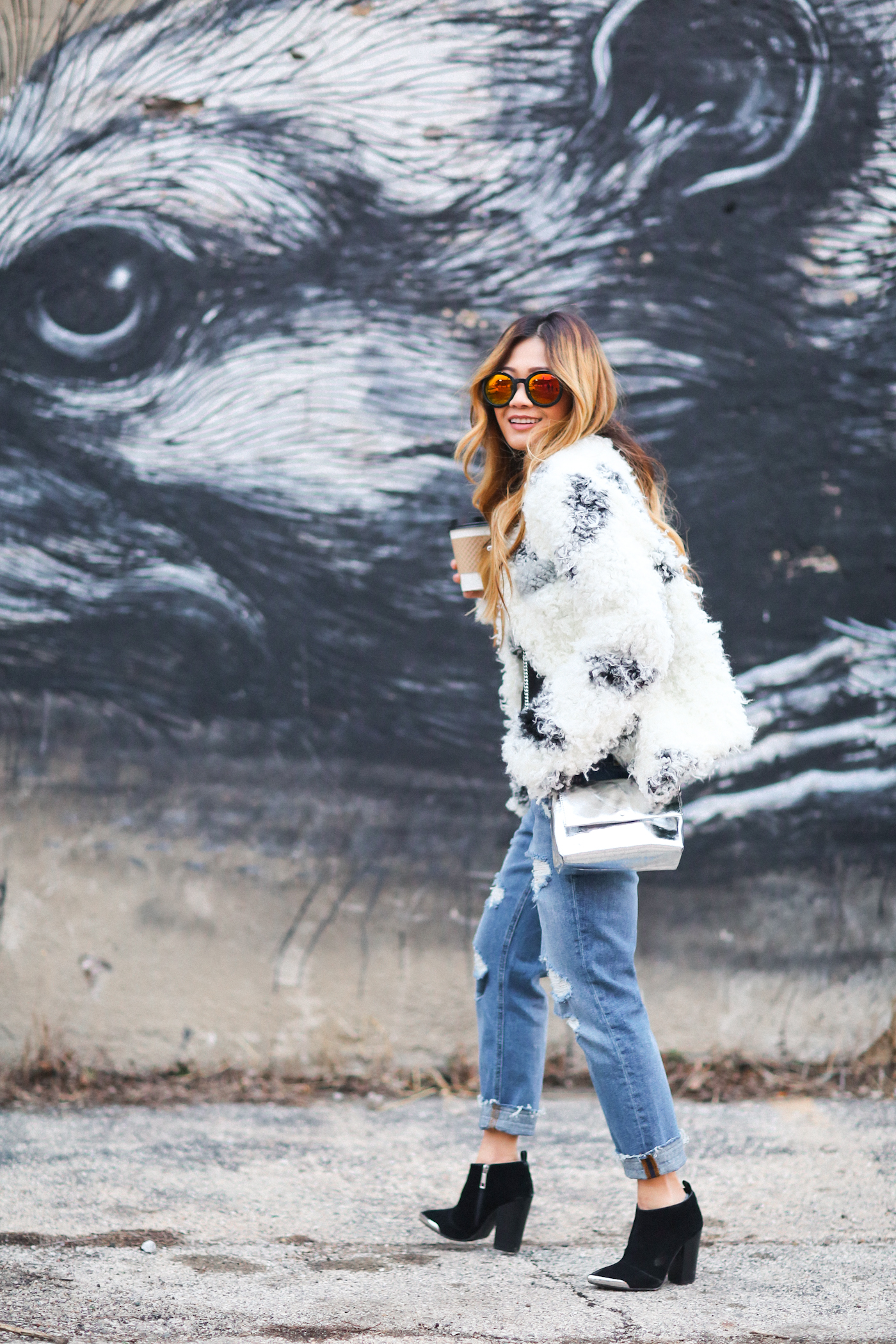 corset top and curly faux fur coat with reflective sunglasses and ripped jeans